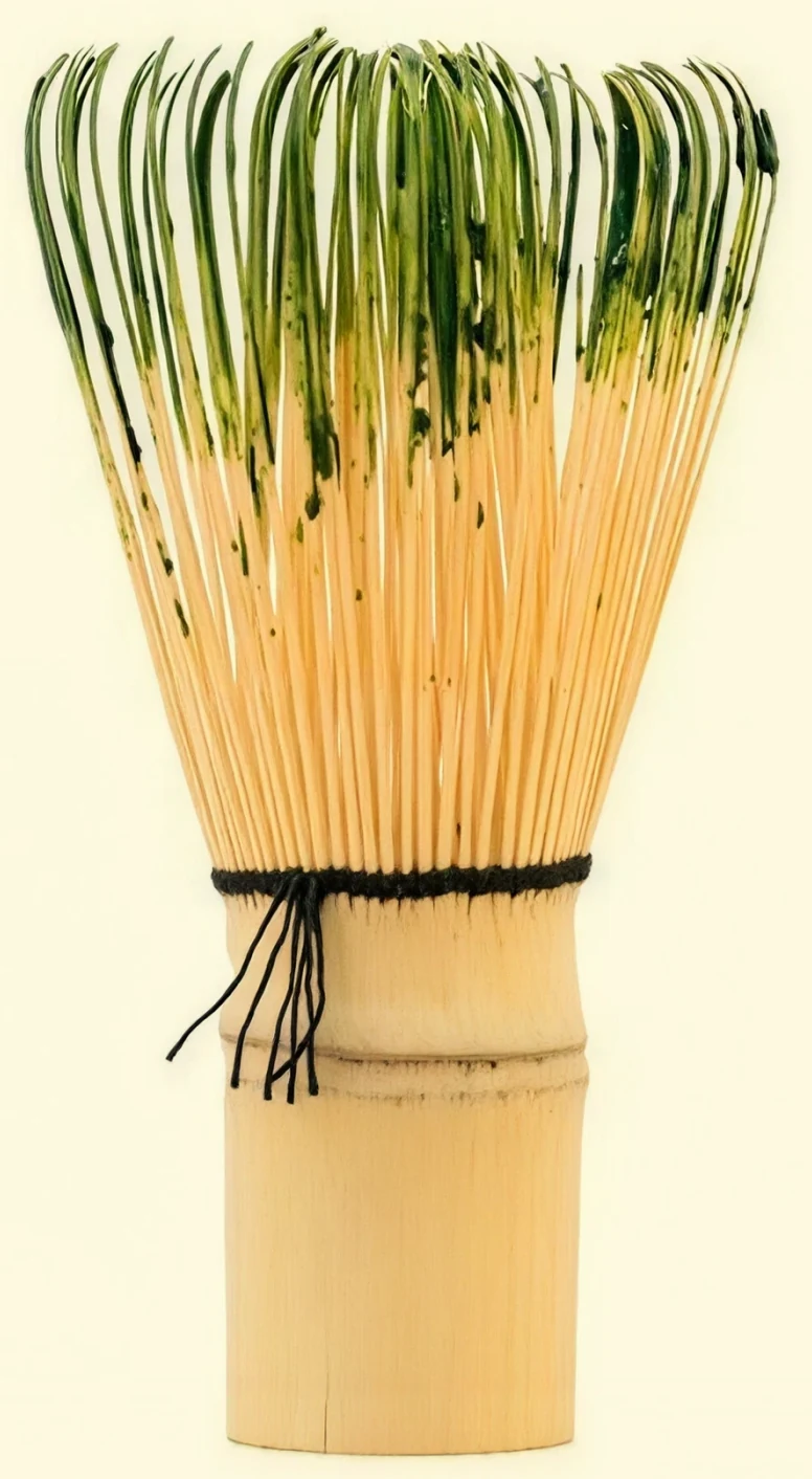 A bamboo chasen stood upright on a cream ground, its tines fanning out from the carved base, the photograph the Atiya symbol is drawn from
