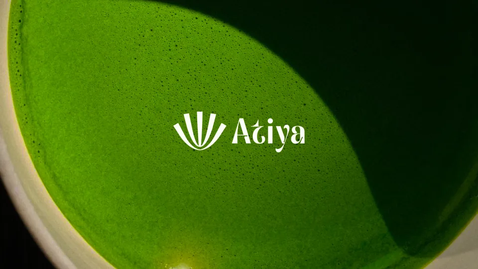Wide crop of the Atiya cover: whisked matcha filling a pale ceramic bowl with the white Atiya logo lockup on the right