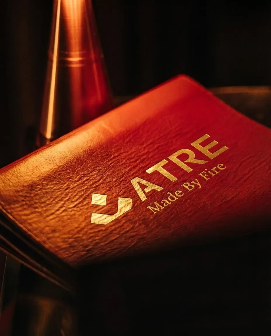 The ATRE menu in gold foil on deep red leather, lit warm