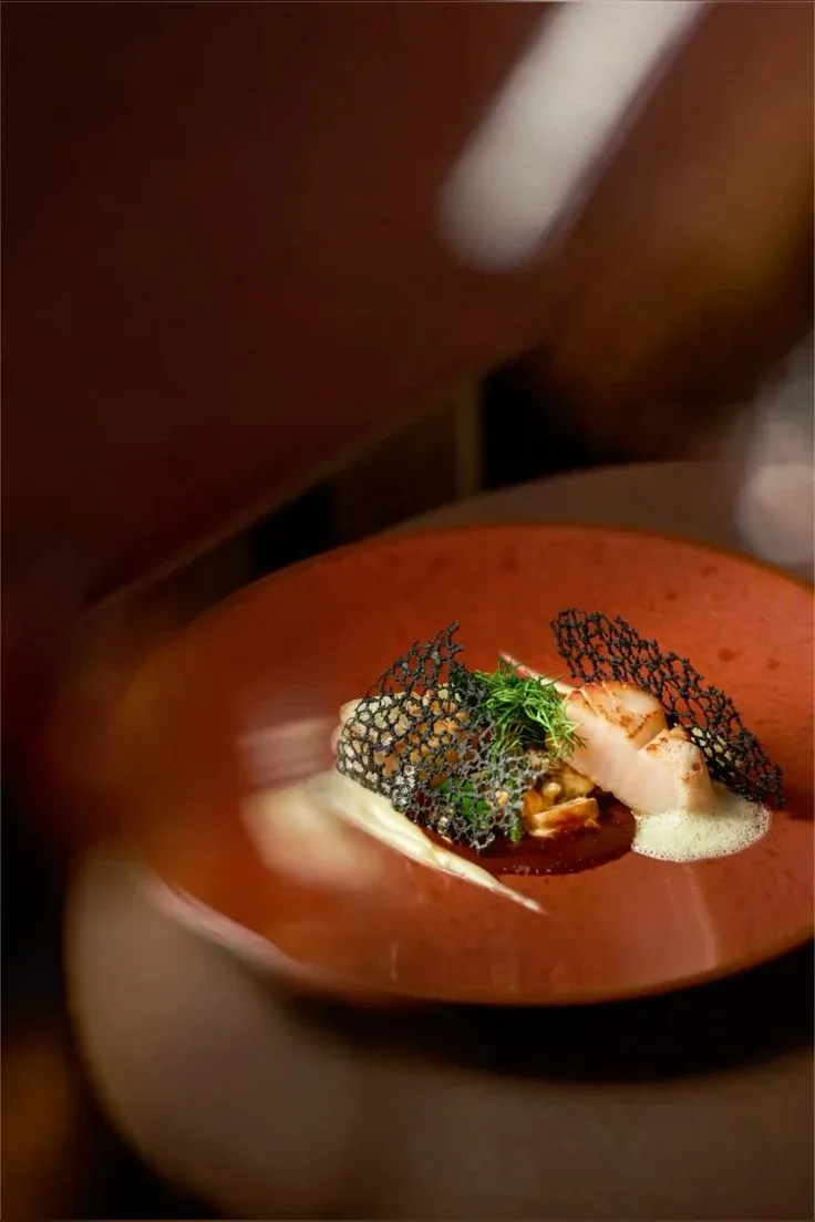 A plated dish on a burnt orange bowl, shot close and warm