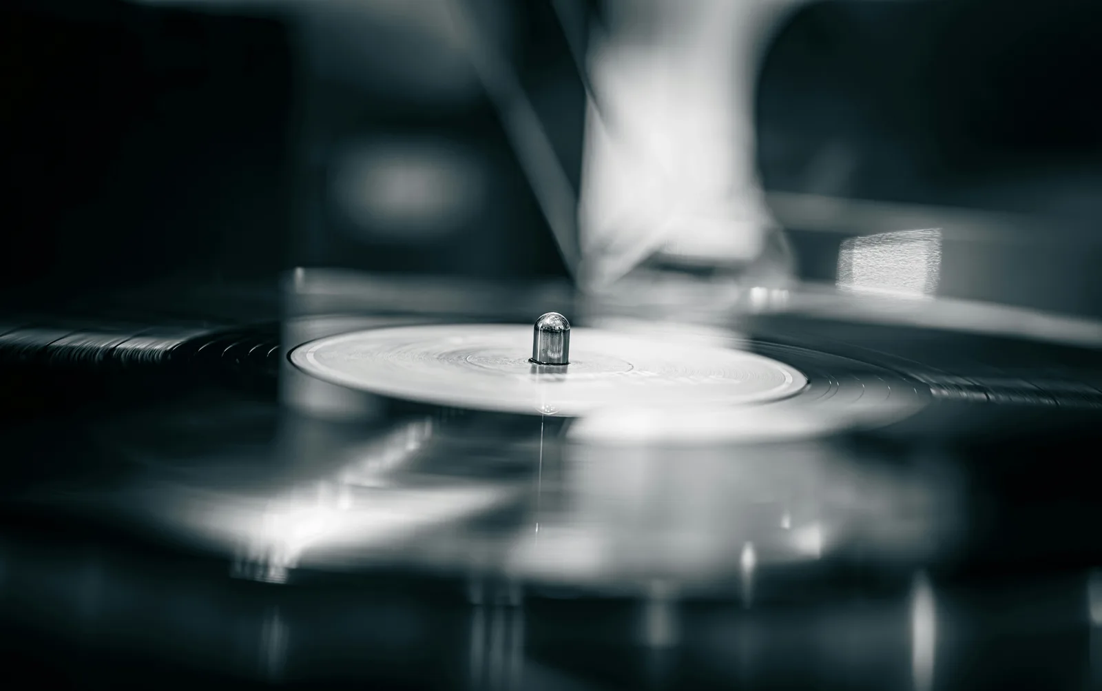 A vinyl record spinning on a turntable spindle, photographed in monochrome