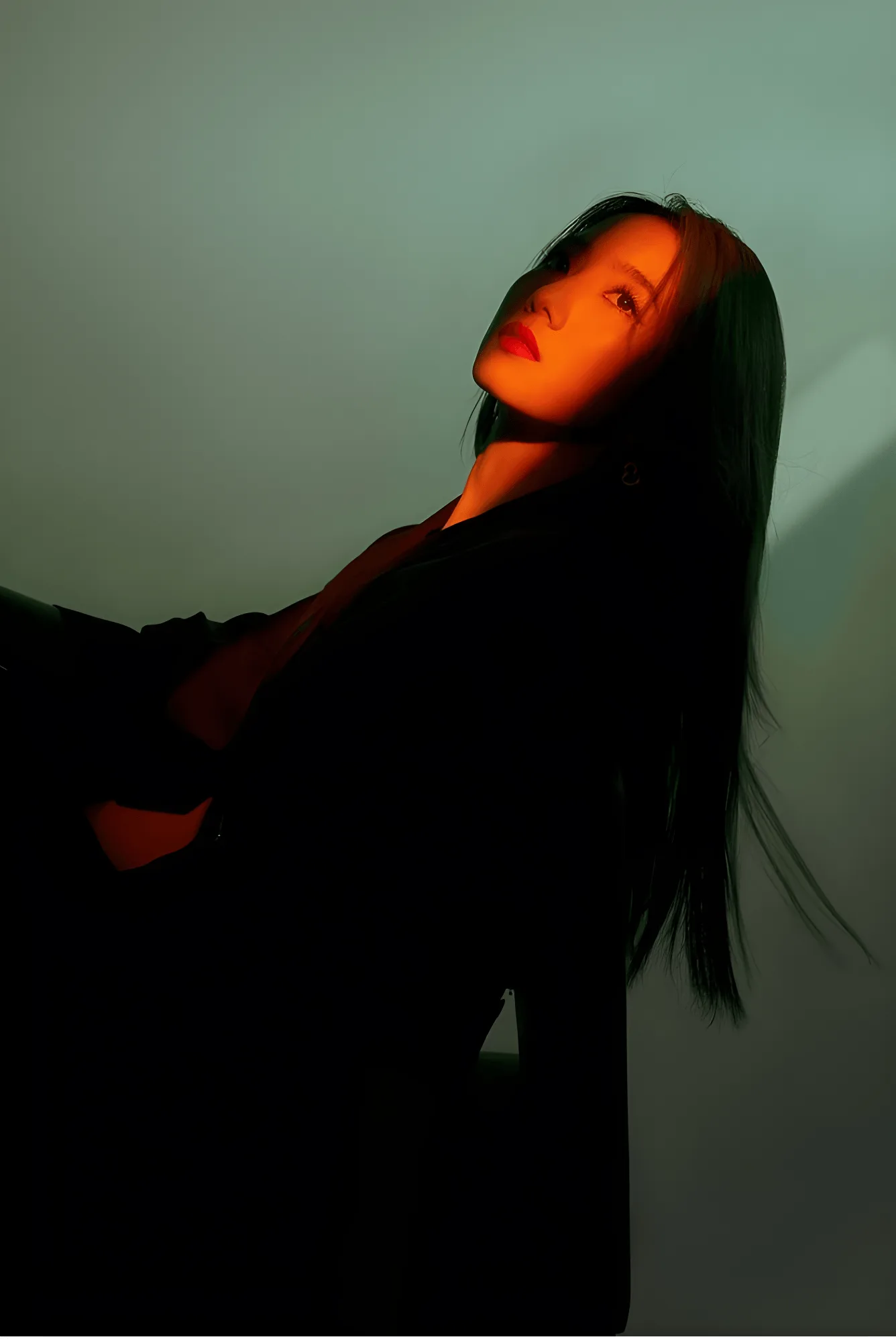 Basis brand photography: a portrait lit in hard orange light against a muted grey wall