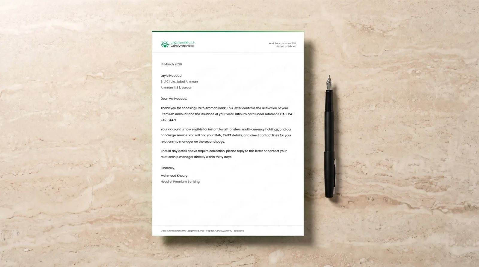Photograph of the Cairo Amman Bank letterhead on a dark linen desk mat with a fountain pen and a blank business card, the letter itself the real document.