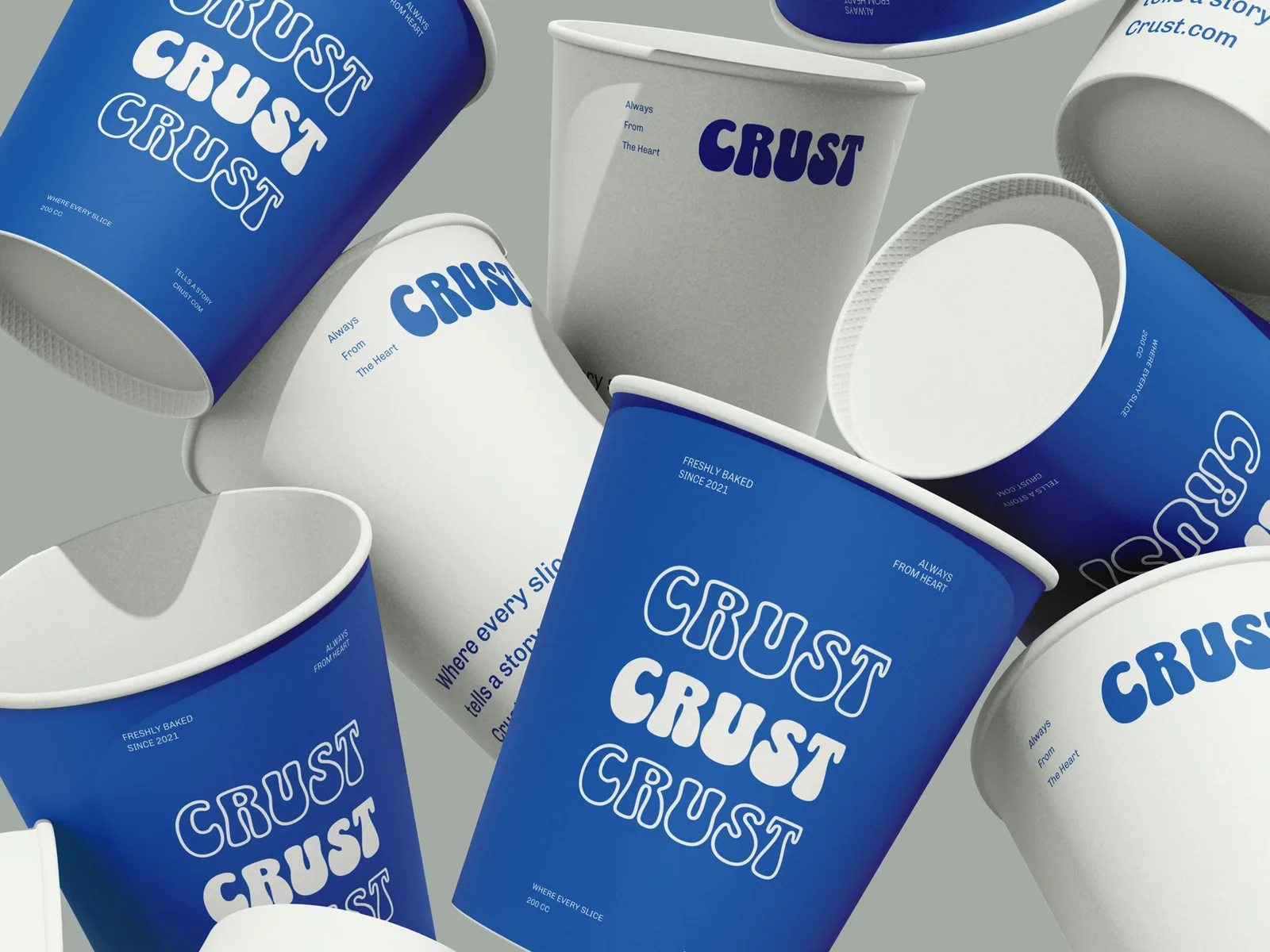 A tumble of CRUST branded paper coffee cups in blue and white, each carrying the rounded wordmark