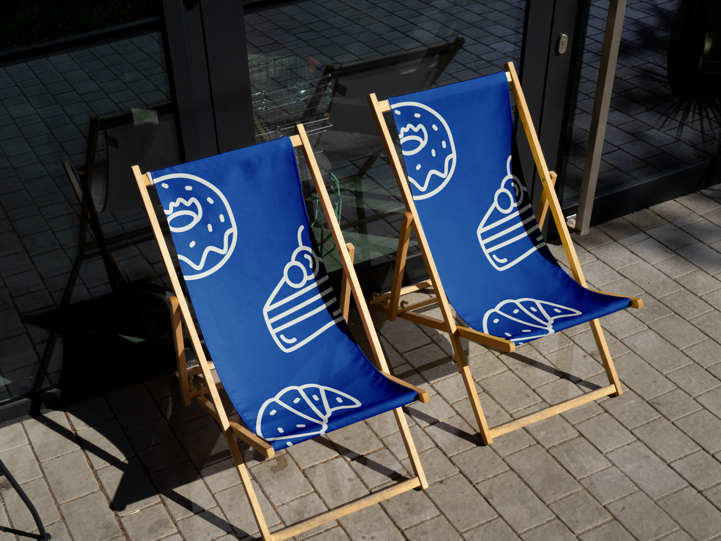 Two deckchairs outside the CRUST shopfront, their blue slings printed with oversized line drawings of a doughnut, a slice of cake and a croissant