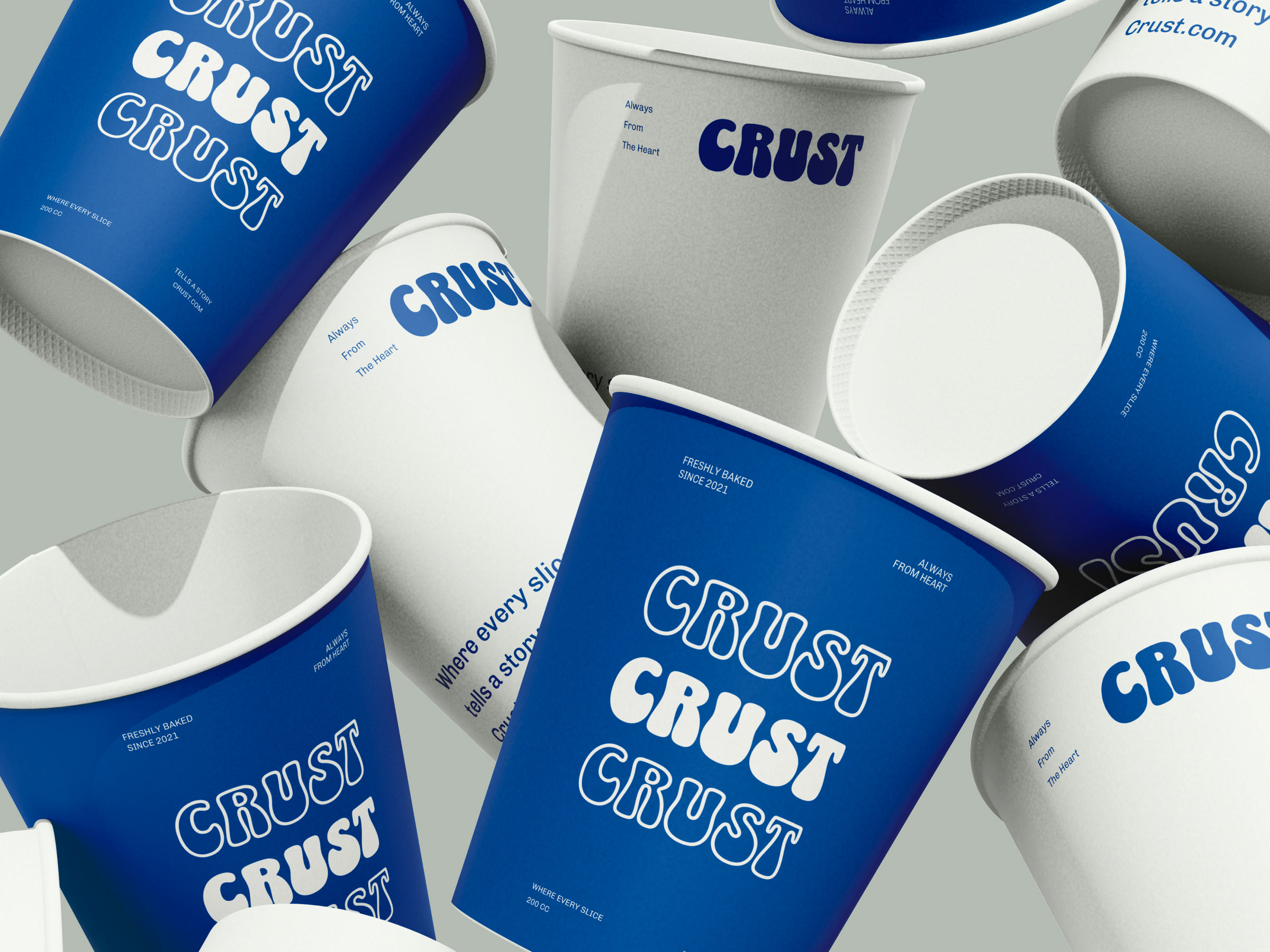 A pile of CRUST takeaway cups in blue and off-white, wordmark repeated three times on each