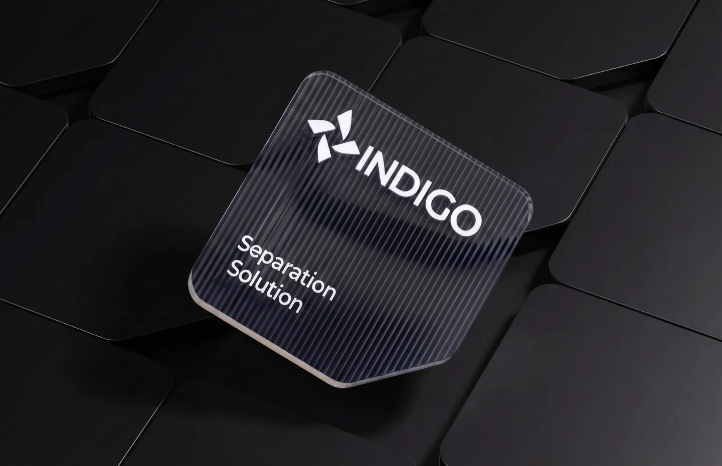 Ribbed glass tile carrying the Indigo pinwheel logo and Separation Solution label, floating over a field of black rounded tiles