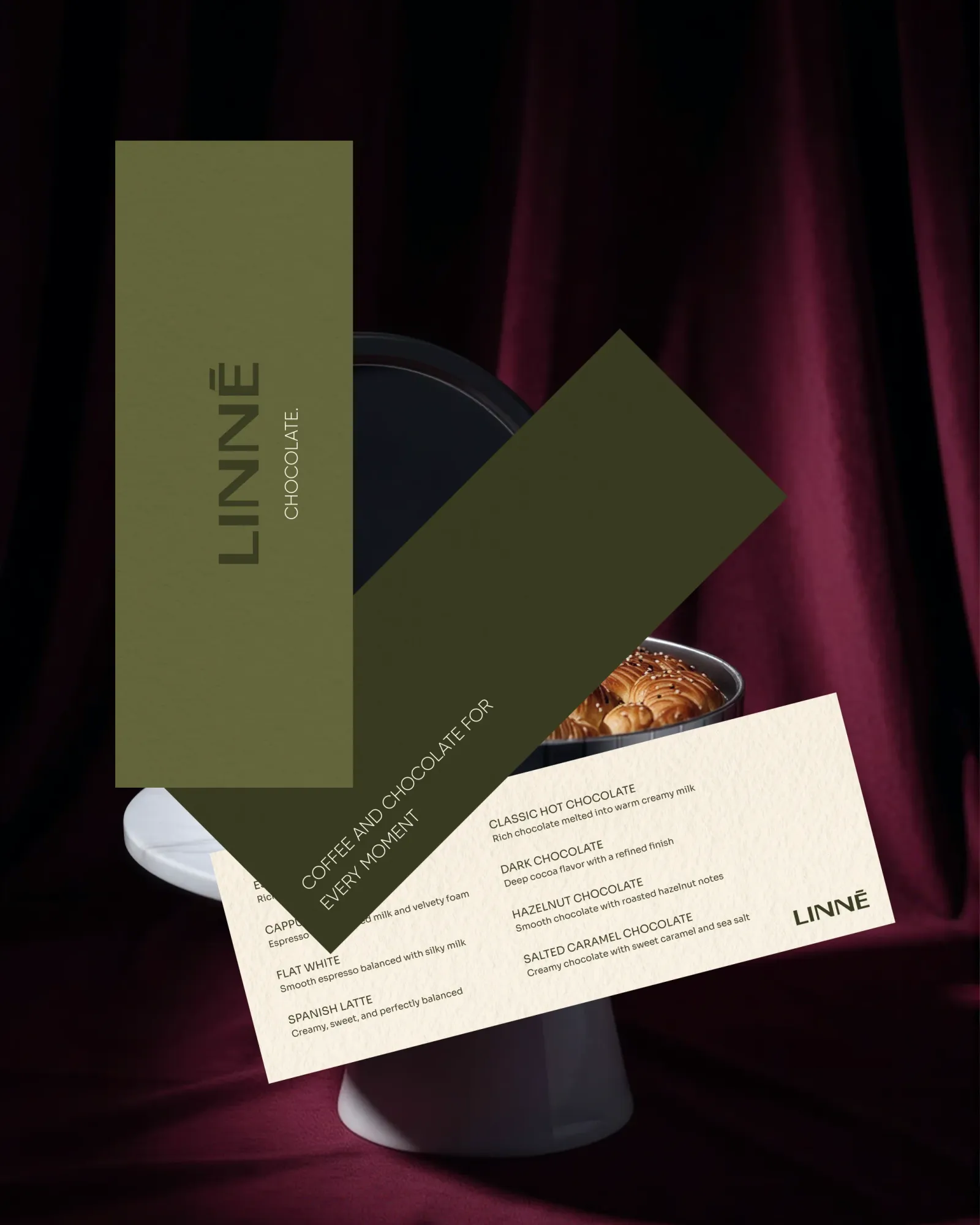 The LINNÉ menu on a round tin over maroon velvet: an olive card with the Latin wordmark, a dark olive card reading Coffee and Chocolate for Every Moment, and a cream card listing the coffees and four hot chocolates.