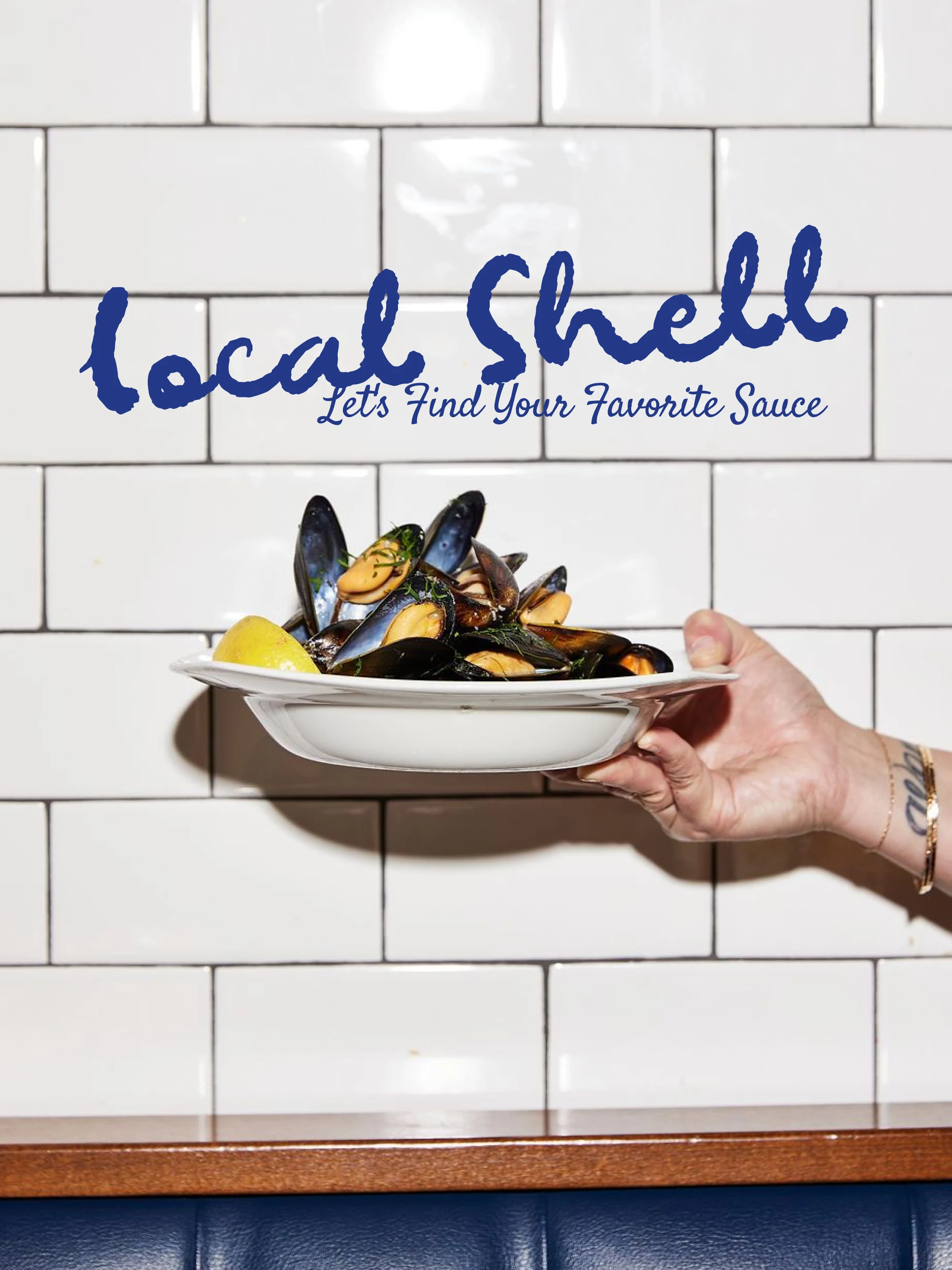 The Local Shell wordmark and its line painted across a white subway-tile wall in brand blue, a hand holding out a bowl of mussels beneath it