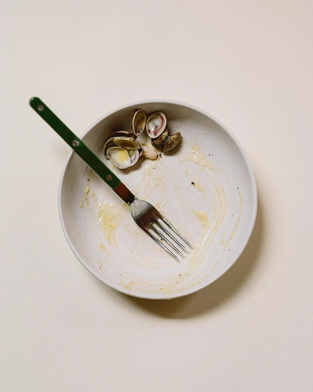 A finished plate seen from above: empty shells, a fork laid across it and the last of the sauce