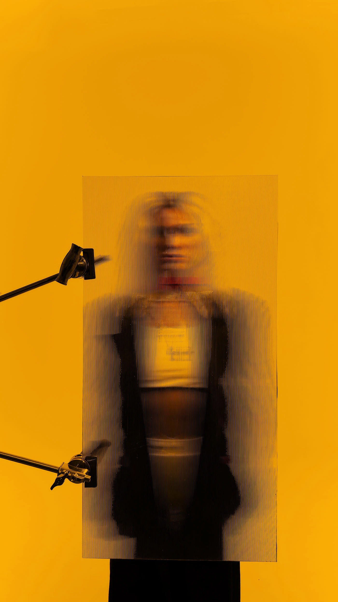A figure smeared into vertical streaks by a long exposure, clamped between two studio stands