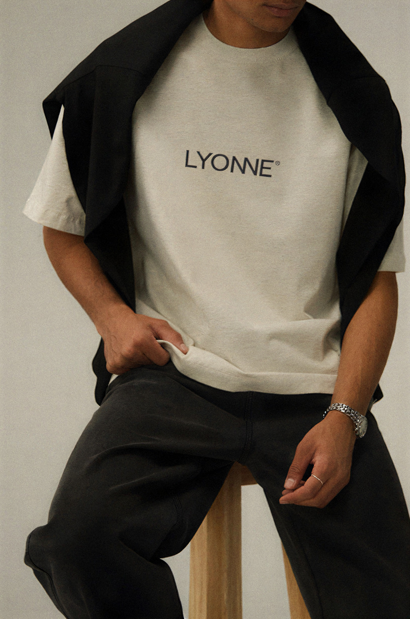 Oat Lyonne t-shirt with the chest wordmark, a black overshirt draped across the shoulders