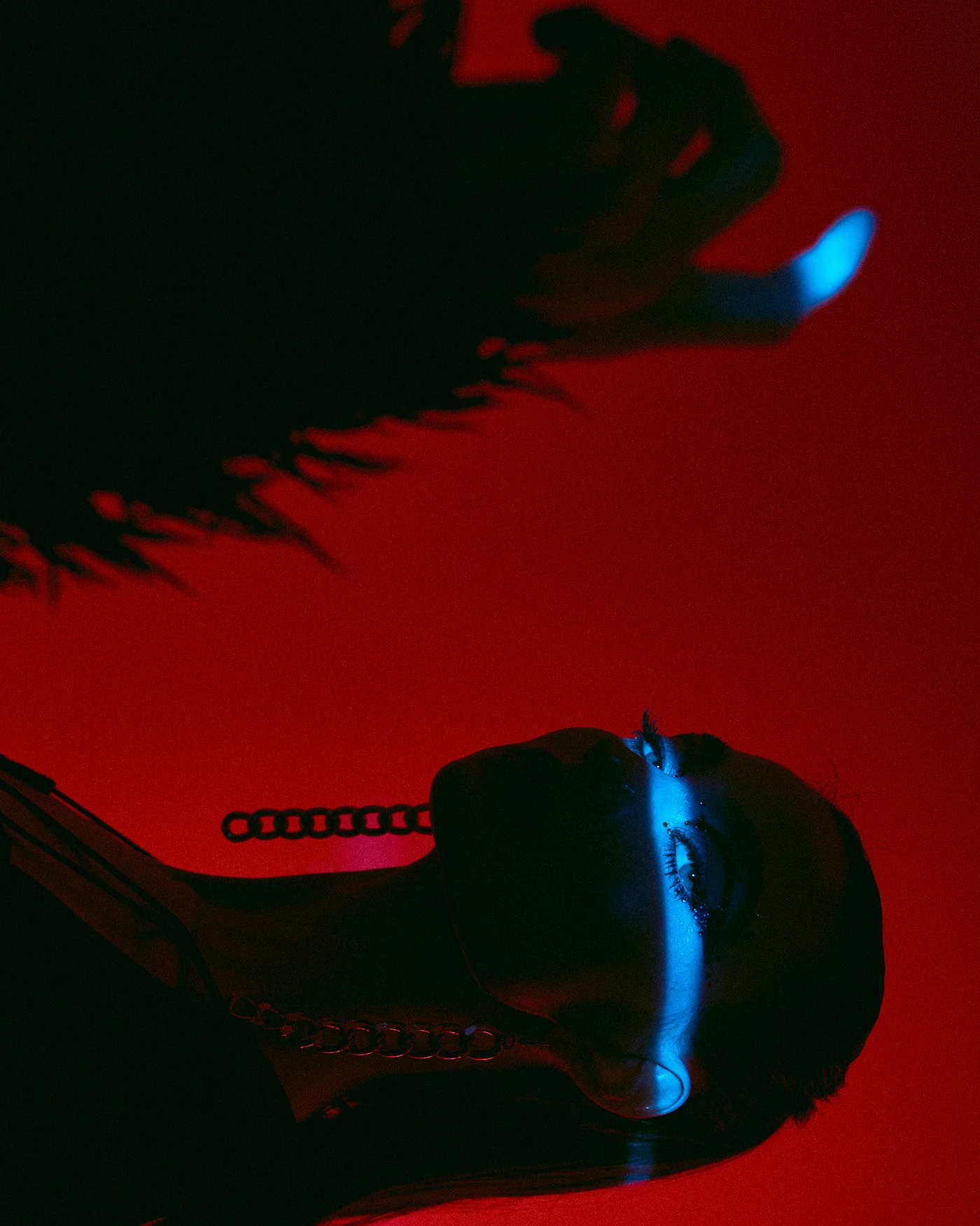 Red gel campaign frame: a model leaning into a wedge of warm light in a striped jacket
