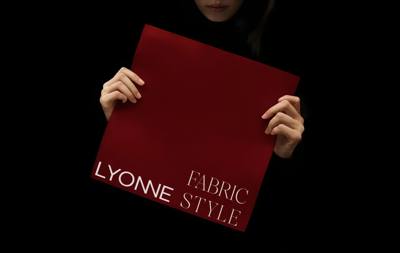 Hands holding a Rosewood red square folder with the serif Lyonne Fabric Style lockup, out of darkness