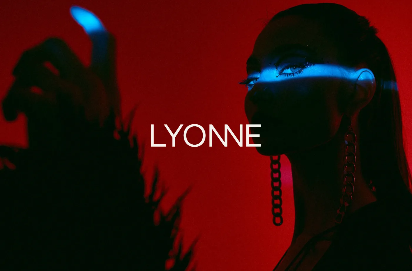 Model in deep red gel light with a blue light bar across the eyes and chain earrings, the white Lyonne wordmark centered