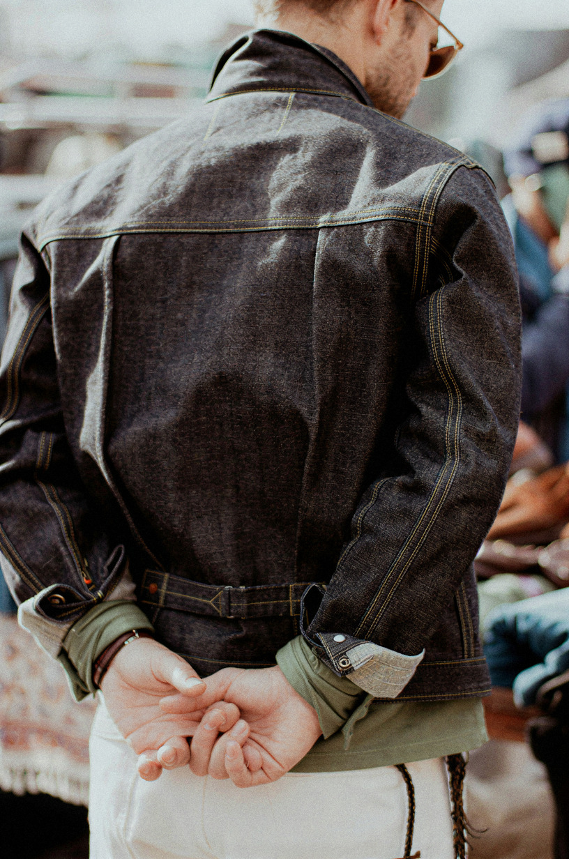 Raw denim jacket seen from behind, hands clasped at the back