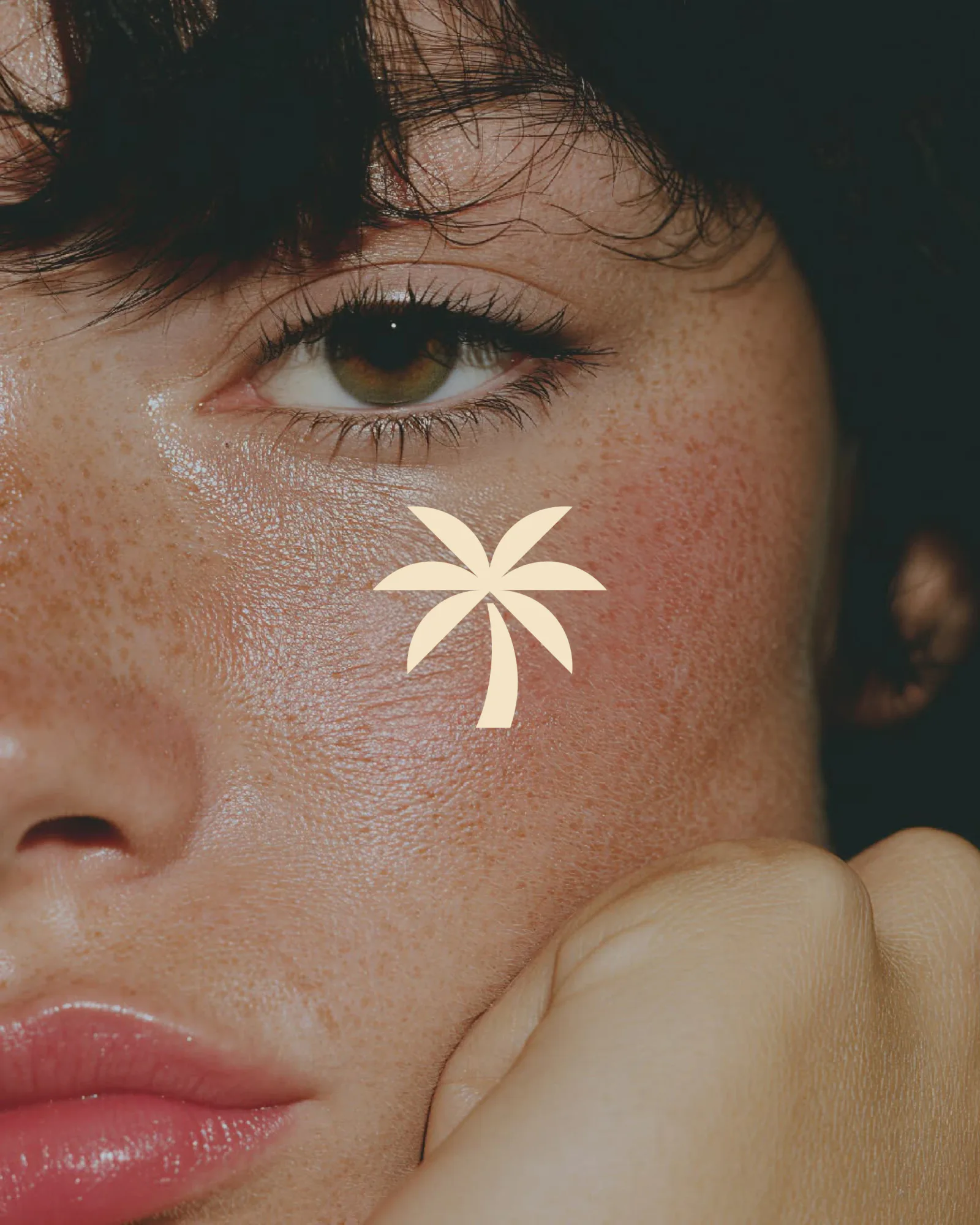 A close portrait with the cream palm mark on a freckled cheek.