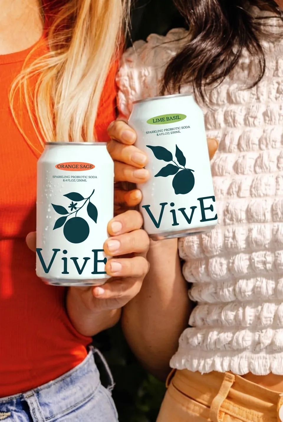 Two friends in the sun holding an Orange Sage and a Lime Basil can side by side